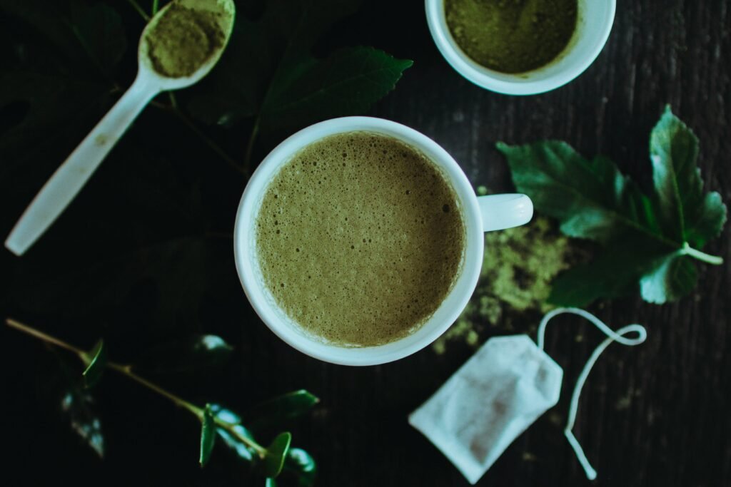 A calming overhead shot of a matcha latte surrounded by leaves and matcha powder for a natural touch.