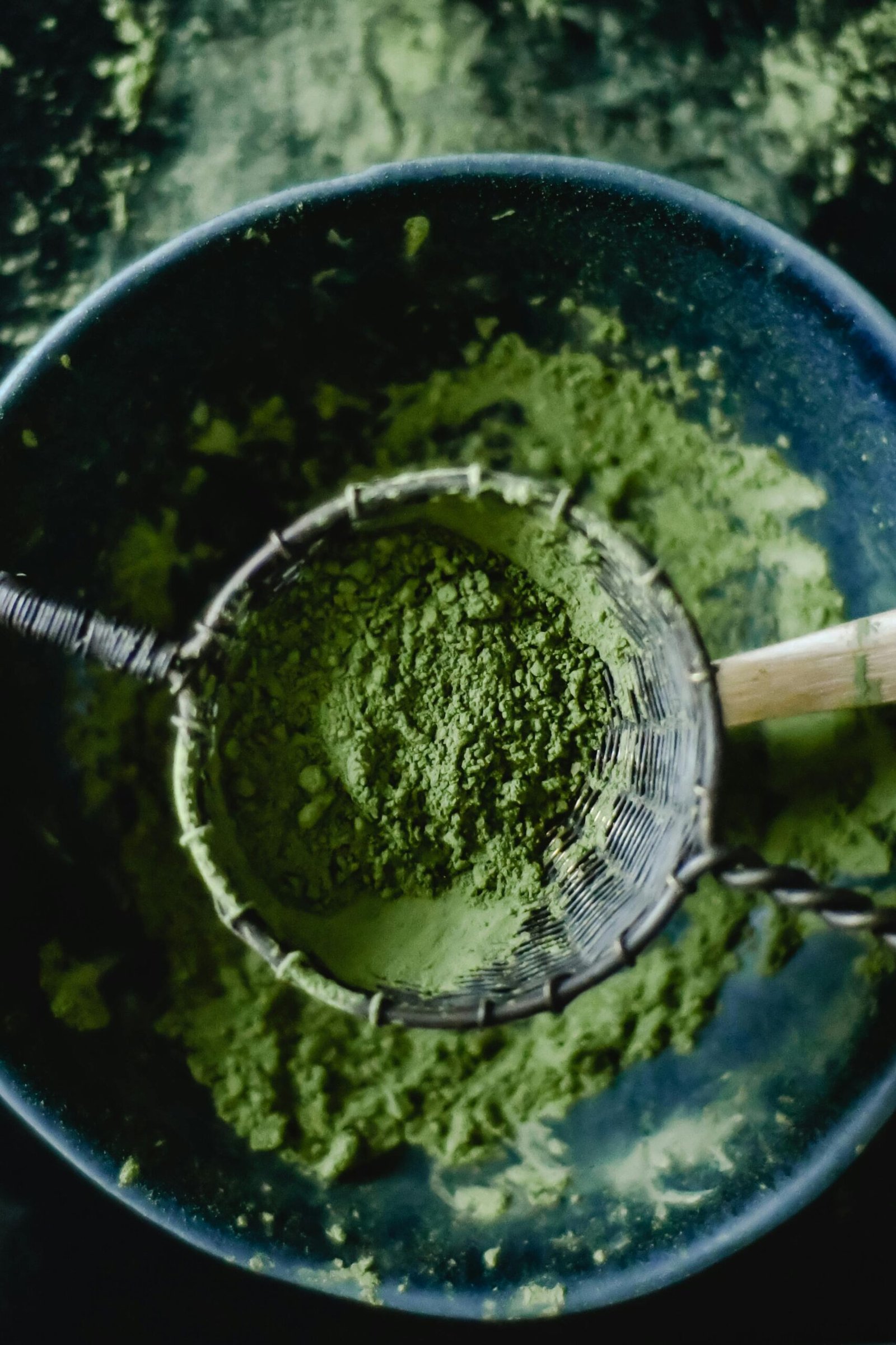 Green tea matcha powder in a sieve placed over a bowl, illustrating a healthy organic lifestyle.